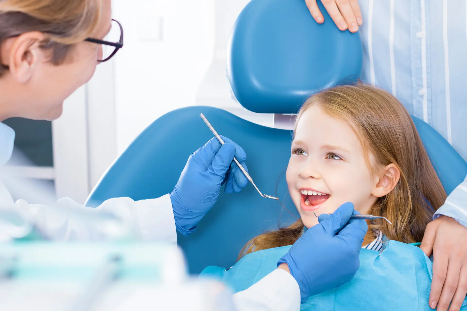 Stock image of a smiling girl in the dental chair with her mouth opened for a dental cleaning, a service offered by Heart Mountain Dental, a dentist in Cody, Wyoming.