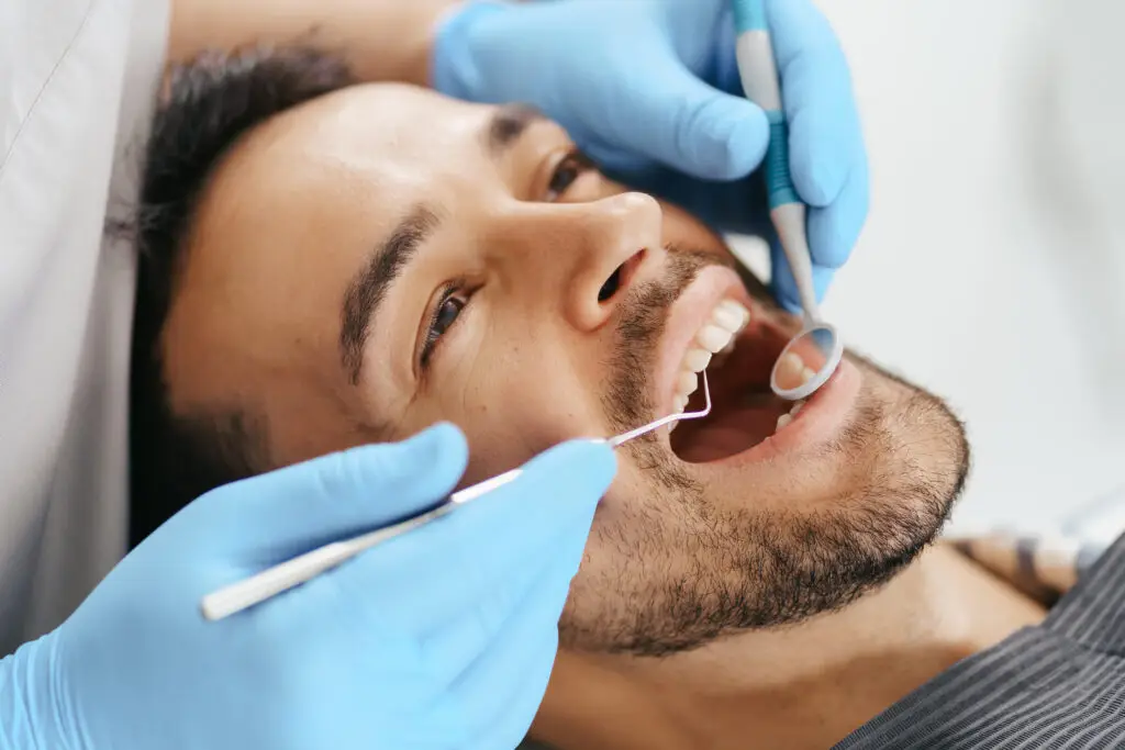 Stock image of young man with mouth open during a dental cleaning