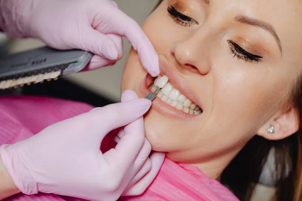 Close-up of a dental veneer being applied to a woman's teeth at a clinic.