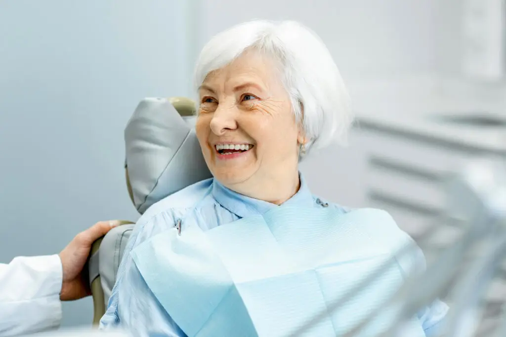 Stock image of an elder woman patient smiling with perfect teeth during a consultation with dentist at the dental office
